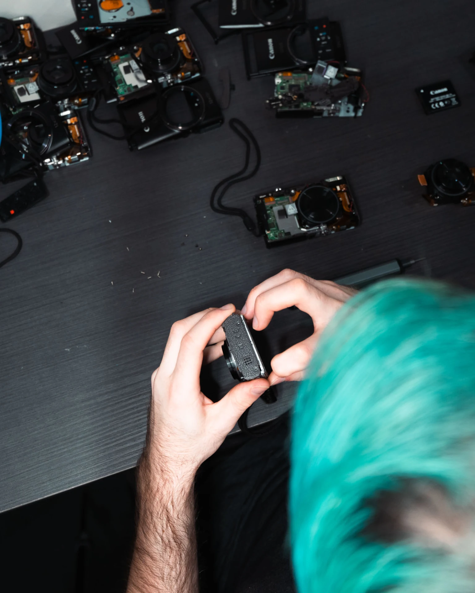 Staff member inspecting a camera, with hands and camera equipment visible on the workbench