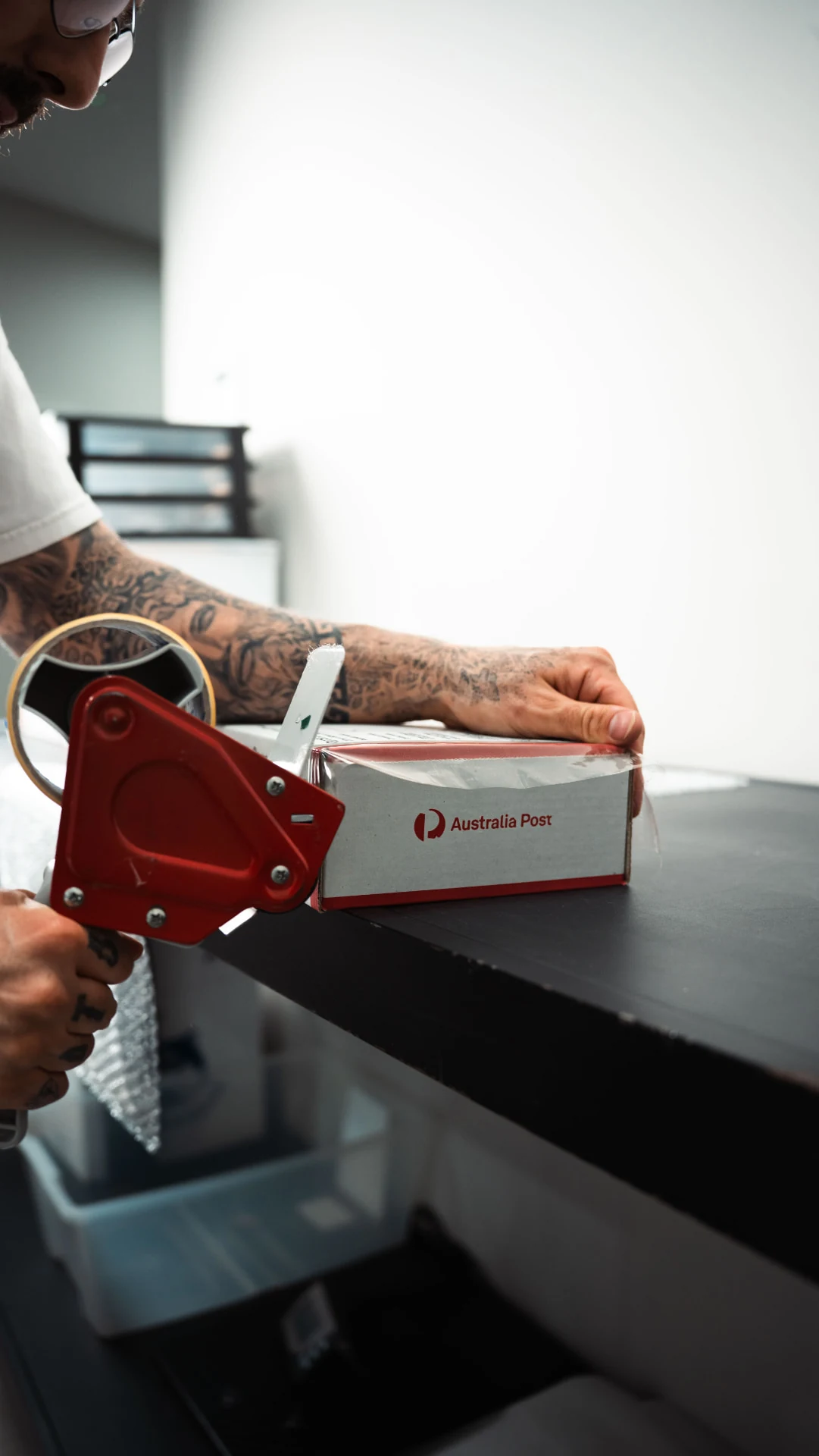 Staff member sealing an Australia Post parcel with a tape dispenser