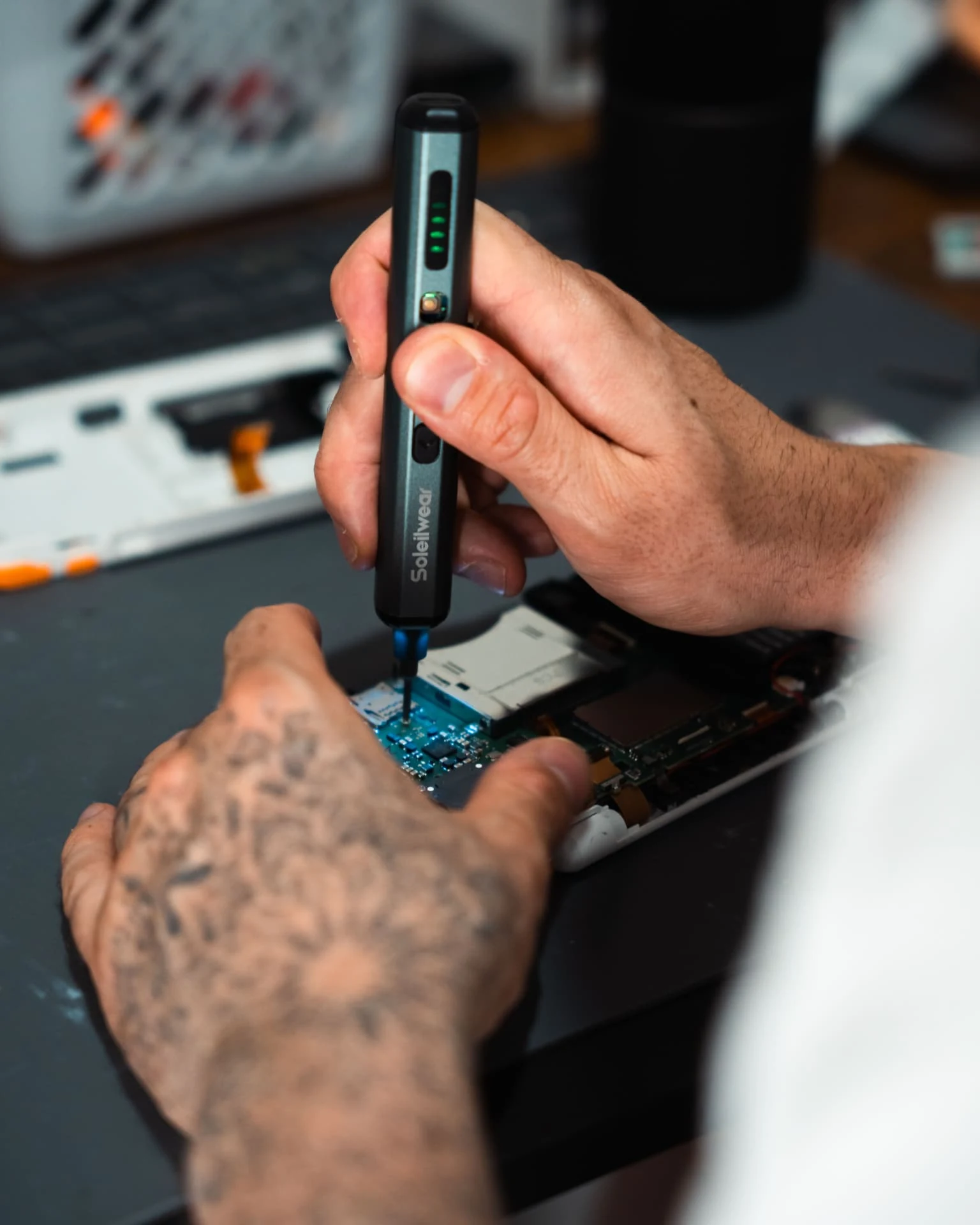 Close-up of hands using tools to repair an electronic device at our workbench