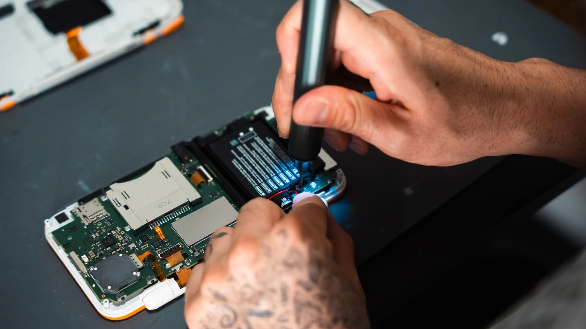 Hands repairing the exposed internal components of an electronic device